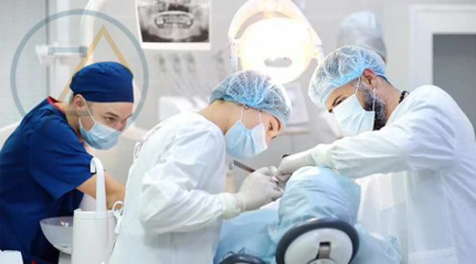 Equipe odontológica realizando procedimento em centro cirúrgico hospitalar com paramentação completa e equipamentos especializados