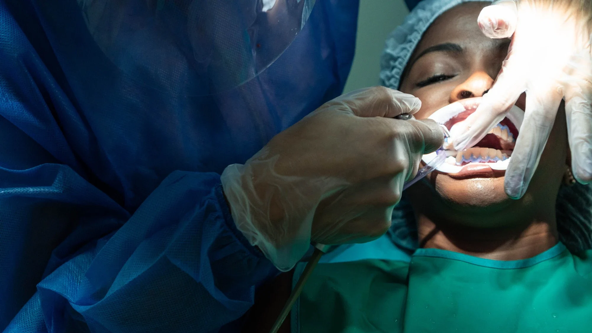Cirurgião dentista realizando procedimento odontológico hospitalar com equipamentos de segurança em centro cirúrgico